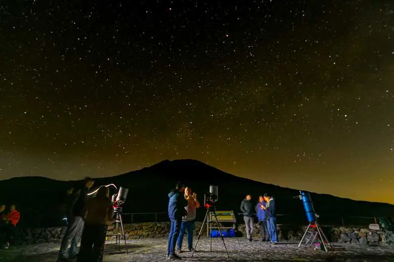 Gente de pie sobre el volcán Teide para observar las estrellas 